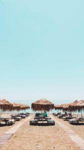 una spiaggia con sedie, ombrelloni di paglia e l'oceano di SeaSideRooms a Ierápetra