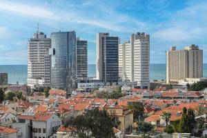 a city with red roofs in front of tall buildings at The Radiant By HolyGuest in Tel Aviv