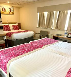 um quarto de hotel com duas camas com lençóis vermelhos e brancos em Clifton Court Hotel em Blackpool