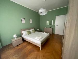 1 dormitorio con 1 cama con paredes verdes y suelo de madera en Cozy Apartment x6 persone, en Turín