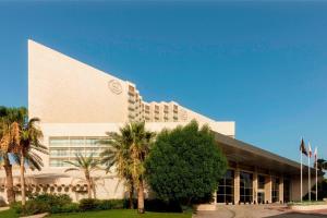 a building with palm trees in front of it at Sheraton Dubai Creek Hotel & Towers in Dubai