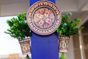 a plate on a pole with two potted plants at The Rina Hostel in Agadir