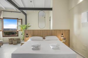 1 dormitorio con 1 cama blanca grande y toallas. en Achatis Suites en Hersonissos