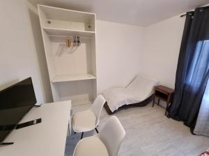 a room with two chairs and a desk and a tv at Chambre cosy in Persan