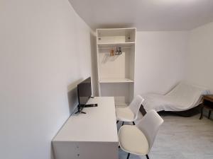 Habitación blanca con 2 sillas, escritorio y cama en Chambre cosy, en Persan