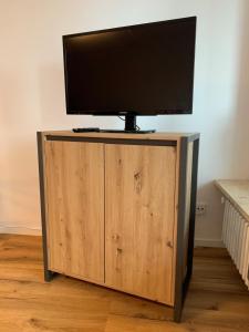 TV de pantalla plana en un soporte de madera con un televisor. en Staufen Herz, en Oberstaufen