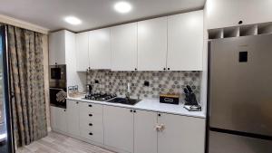 een keuken met witte kasten en een roestvrijstalen koelkast bij Apartment Rustaveli 118 in Koetaisi