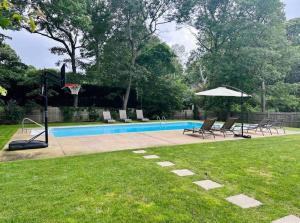 a pool with chairs and a basketball hoop and an umbrella at Nature's Haven in the Hamptons in East Hampton