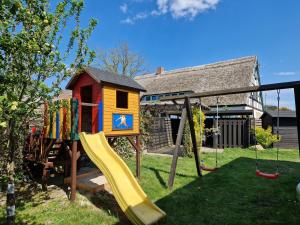 un parque infantil con tobogán y una casa de juegos en Zinnowitz, Haus Jörn en Zinnowitz