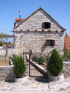 a stone building with a gate and bushes in front of it at Augustinovi Dvori in Škrip