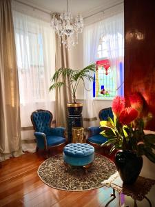 a living room with blue chairs and a chandelier at The Old Eltham Post Office in Eltham