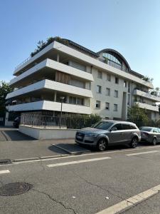 twee auto's geparkeerd voor een gebouw bij Charme et Confort à Borderouge in Toulouse