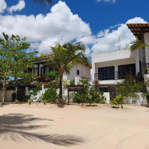 a building on the beach with a palm tree in front at Agapanthus Apartamentos in Jericoacoara