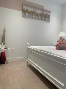 Un dormitorio blanco con una cama con un animal de peluche. en Brand new 1Queenbed family suite near UBC en Vancouver