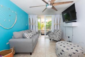 a living room with a couch and a flat screen tv at Coqui Beach Home, Paseo del Faro Combate in Cabo Rojo