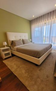 ein Schlafzimmer mit einem großen Bett und einem großen Fenster in der Unterkunft Casa da Praia in Vila Nova de Gaia