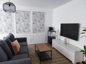 a living room with a couch and a tv and two windows at Proche de Paris T3 tout confort in Courcouronnes