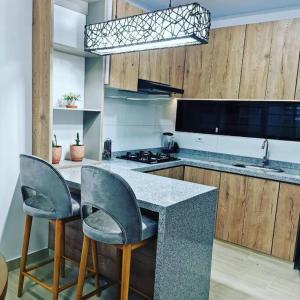 kuchnia z blatem z 2 krzesłami i kuchenką w obiekcie Nuevo y lindo apartamento w mieście Yopal
