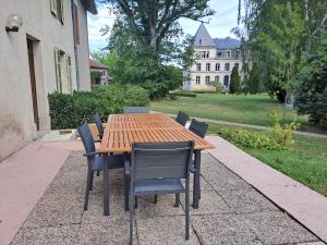 a wooden table and chairs with a house in the background at Maison du parc 