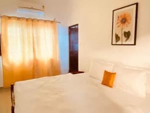 a bedroom with a white bed with a sunflower picture on the wall at Fortis Rooms in Cochin