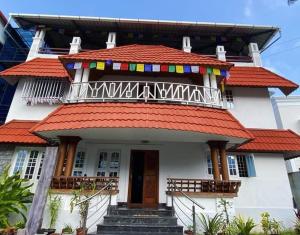 a white house with an orange roof and stairs at Fortis Rooms in Cochin