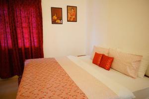 a bedroom with a bed with two red pillows at Fortis Rooms in Cochin