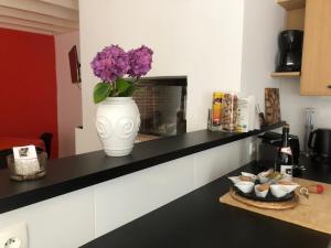 um vaso com flores roxas num balcão na cozinha em LA MABONNAIS em Pleurtuit