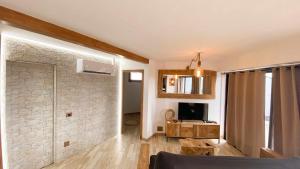 ein Wohnzimmer mit einem TV und einer Steinmauer in der Unterkunft Bungalow Allende Famara con piscina privada y AC in Famara