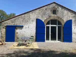 ein Gebäude mit blauen Türen und einem Tisch davor in der Unterkunft Le Cysphée chez Christelle in Sallertaine