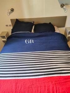 a bed with a blue and white striped blanket on it at Paisible in Agde