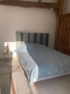 ein Bett mit blauer Decke in einem Schlafzimmer in der Unterkunft Le Cysphée chez Christelle in Sallertaine