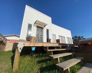 a house with a porch and two benches in front of it at Hostal LV in Los Vilos