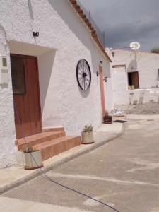 een wit gebouw met een deur en een wiel erop bij Cuevas Alia in Castilléjar