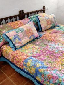 een bed met een kleurrijke quilt en kussens erop bij Cuevas Alia in Castilléjar