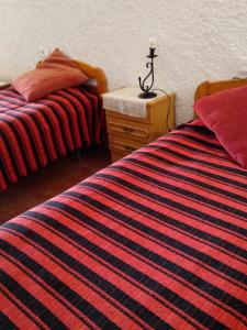 ein Schlafzimmer mit 2 Betten und einem Nachttisch mit einer gestreiften Decke in der Unterkunft Cuevas Alia in Castilléjar