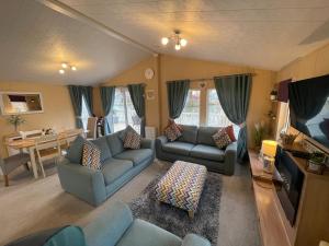 a living room with blue couches and a table at Luxury Lakeside Lodge L2 with Hot tub situated at Tattershall Lakes Country Park in Tattershall