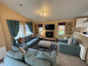 a living room with blue couches and a tv at Luxury Lakeside Lodge L2 with Hot tub situated at Tattershall Lakes Country Park in Tattershall