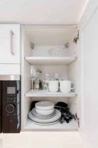 a kitchen with plates and cups and a microwave at Well-Positioned Studio Flat in London