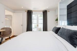 1 dormitorio con 1 cama blanca grande y 1 silla en Well-Positioned Studio Flat, en Londres