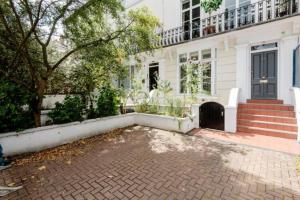 a white house with a brick driveway in front of it at Well-Positioned Studio Flat in London