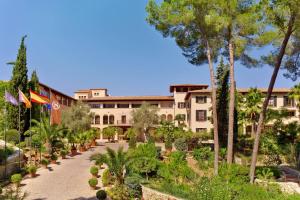 Sheraton Mallorca Arabella Golf Hotel في بالما دي ميورقة: اطلالة على مبنى به اشجار ونباتات