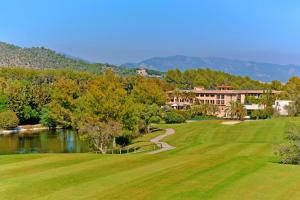 Sheraton Mallorca Arabella Golf Hotel في بالما دي ميورقة: ملعب قولف مع بحيرة ومبنى