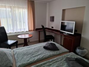 ein Hotelzimmer mit einem Bett und einem Flachbild-TV in der Unterkunft Traditionshotel Goldener Löwe in Zeulenroda