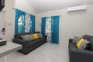 un soggiorno con 2 divani e tende blu di Osmax Oasis entire house/2 bedrooms! a Discovery Bay