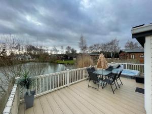 a wooden deck with a table and chairs on it at Luxury Lakeside Lodge L2 with Hot tub situated at Tattershall Lakes Country Park in Tattershall