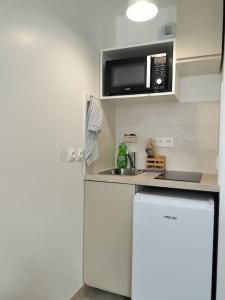 uma pequena cozinha com um micro-ondas e um frigorífico em Studio Paris Sud à côté du métro em Villejuif