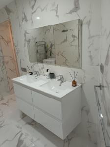 uma casa de banho branca com um lavatório e um espelho em Patalavaca, aguamarina em Patalavaca