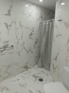 uma casa de banho branca com um chuveiro e uma cortina de chuveiro em Patalavaca, aguamarina em Patalavaca