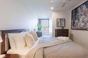 um quarto com uma cama grande com lençóis brancos e almofadas em Luxurious 2 Bed City Scape Retreat with Rooftop em Brisbane