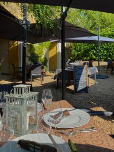 a table with wine glasses and an umbrella at Hôtel-Restaurant-Chambre Insolite Spa - Le XII de Luynes in Luynes